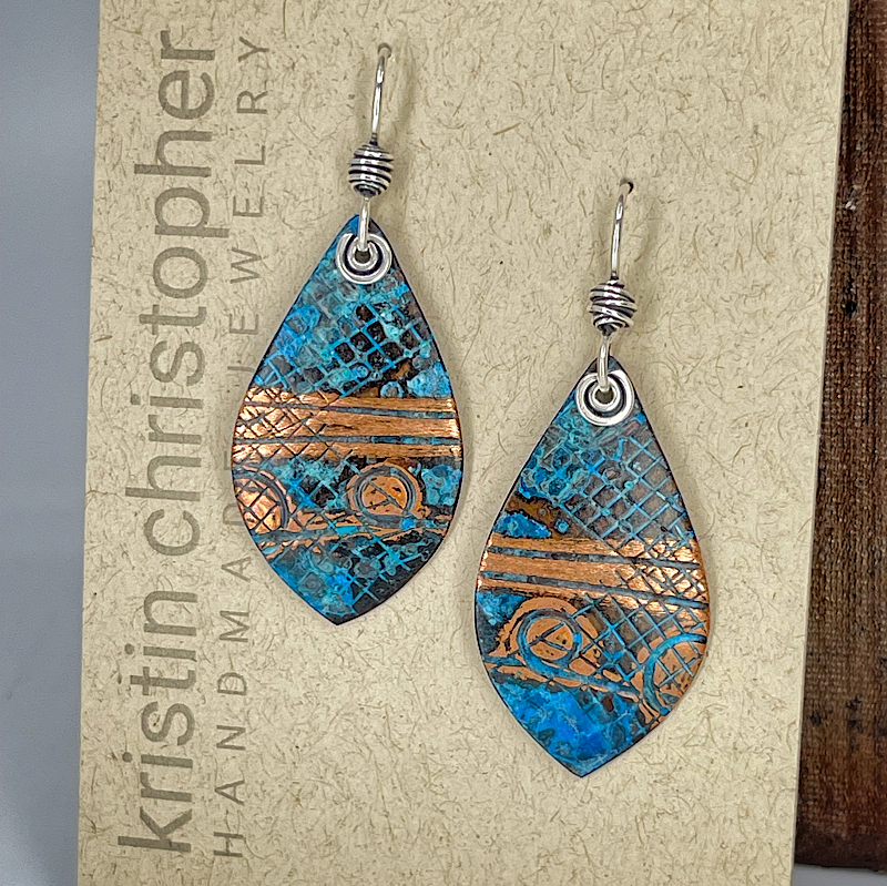 Teardrop-shaped earrings with blue and copper pattern on a 'Kristin Christopher' card.