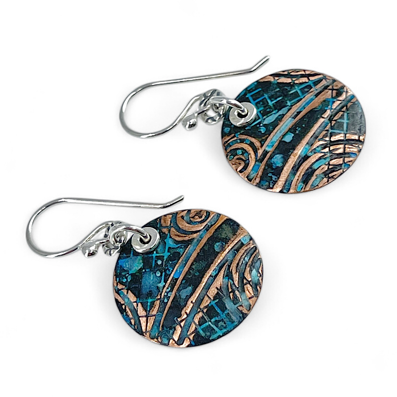 Pair of copper blue patina earrings with abstract design on white background