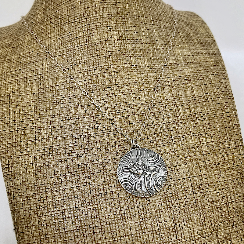 Silver heart and spirals necklac shown on a linen bust