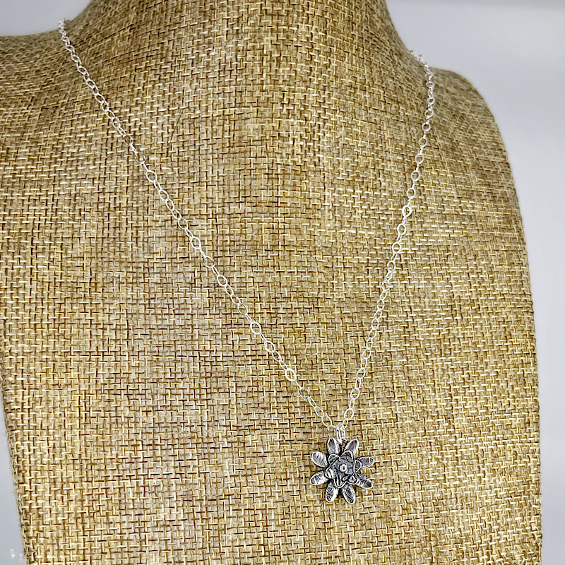 Silver flower pendant shown on linen bust