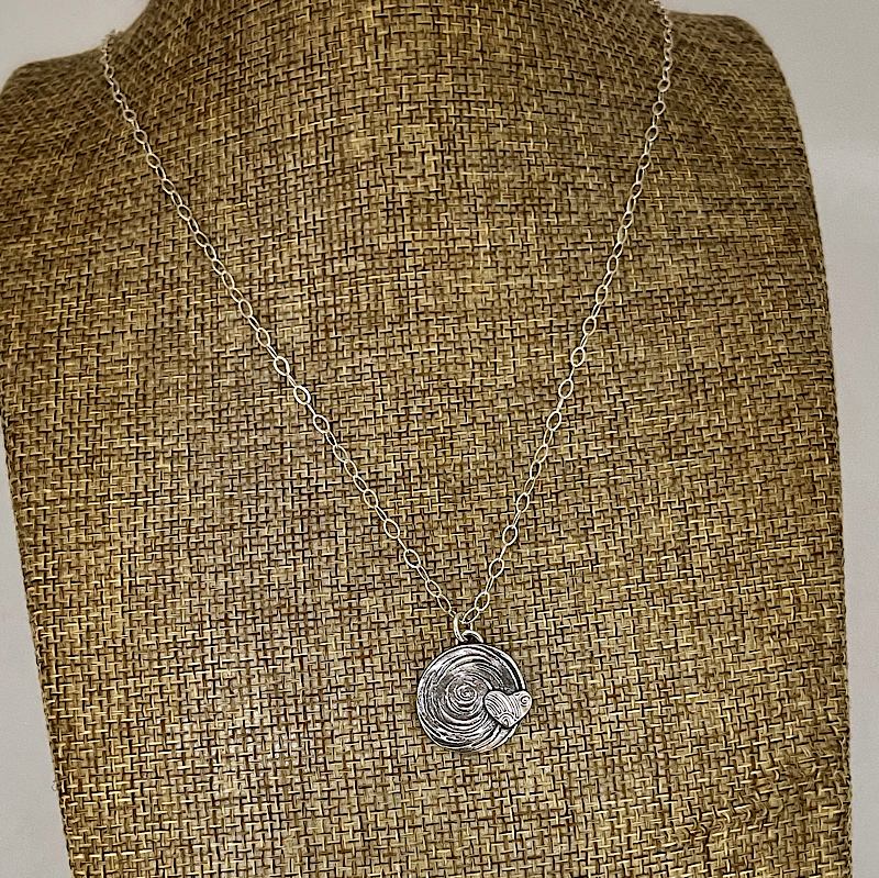 Silver heart necklace on a linen bust
