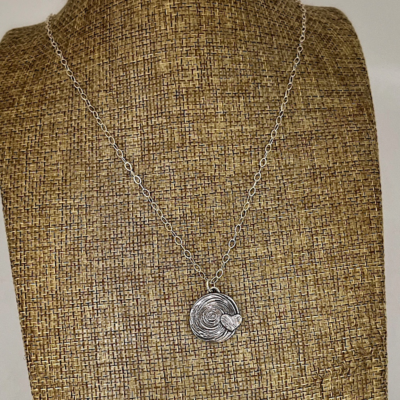 Silver heart necklace on a linen bust