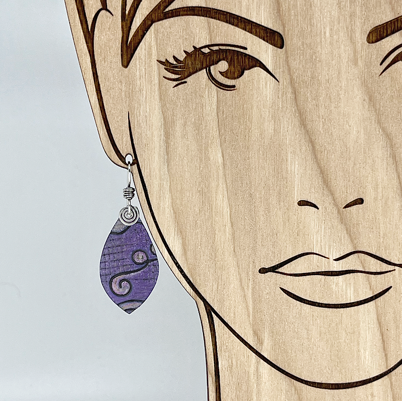 Purple earring with silver spirals on a model