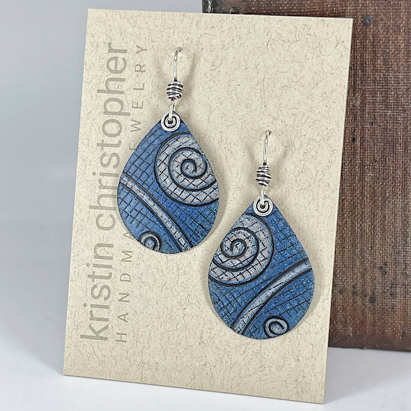 Blue and silver spiral patterned earrings on a 'Kristin Christopher' branded card.