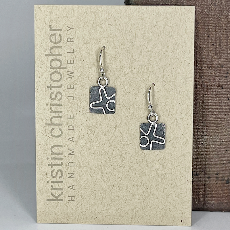 Pair of square silver earrings on a 'Kristin Christopher' branded card.