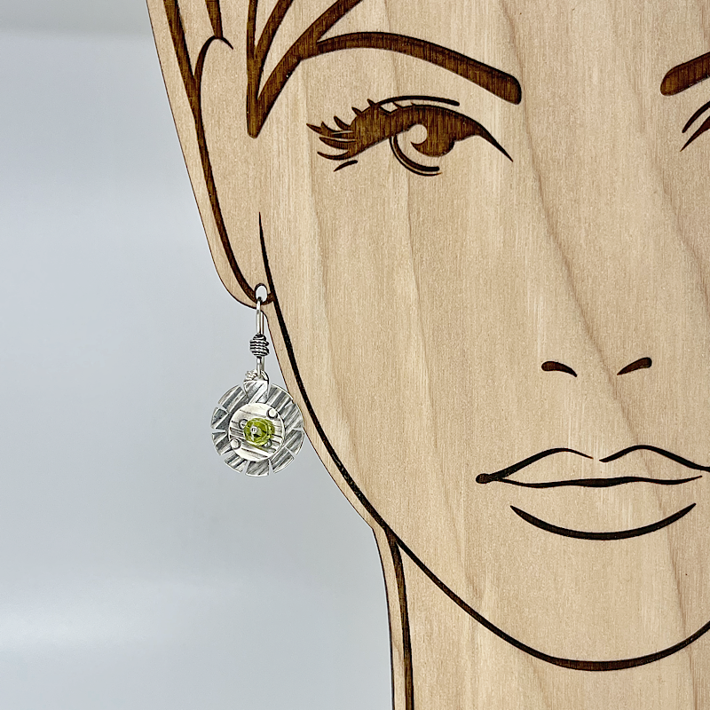 Sterling Silver flower earrings with green peridot shown on a model