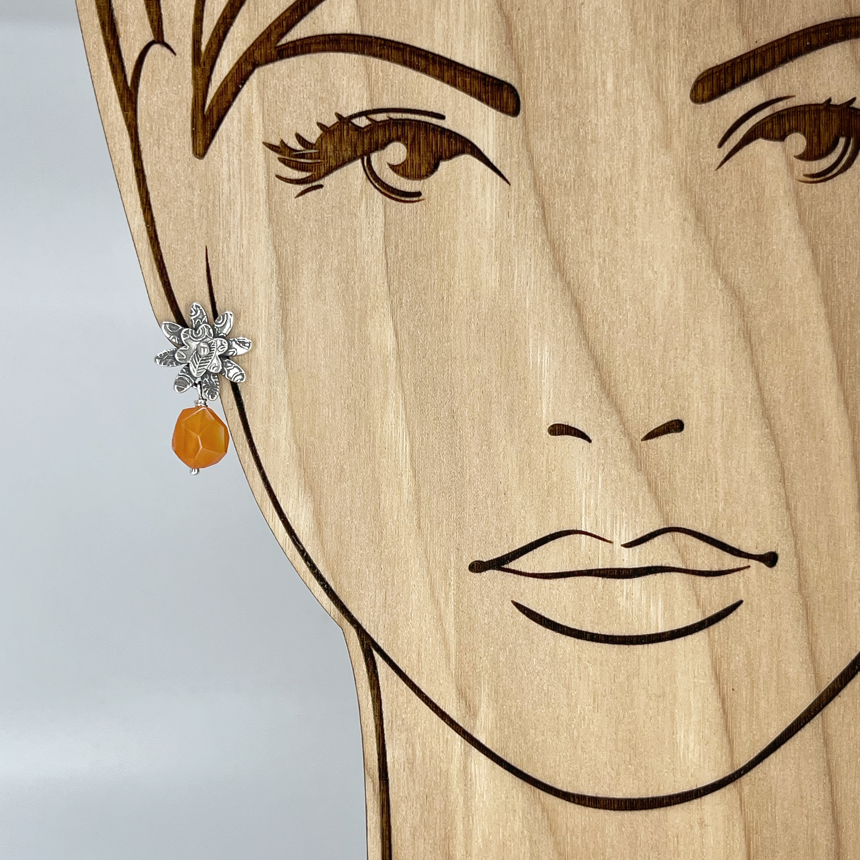 Sterling Silver Flower Earring with orange gemstone shown on model