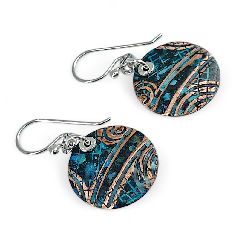 Pair of copper blue patina earrings with abstract design on white background