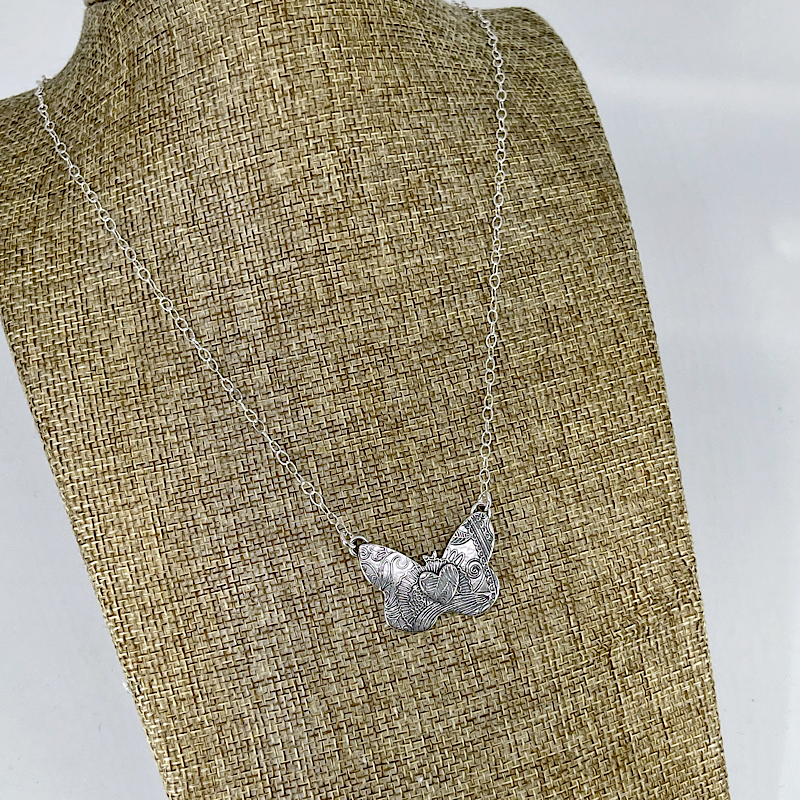 Sterling silver butterfly pendant with heart shown on a linen bust