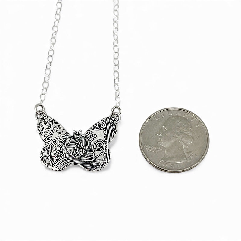 Sterling silver butterfly pendant shown next to a quarter to show comparable size