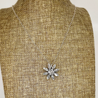 Silver necklace with a floral pendant on a mannequin bust.