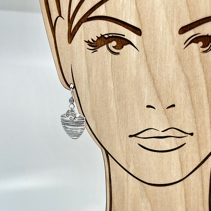 Triangle silver earring shown on model for scale.