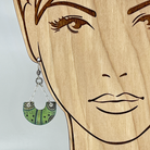 Green, black, and silver earrings shown on a model for scale