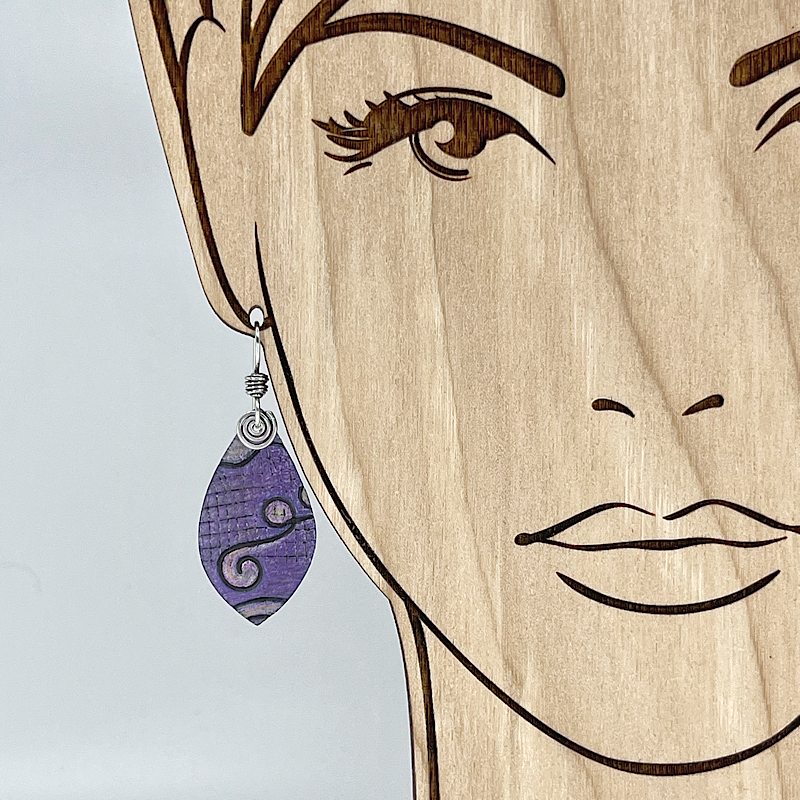 Purple earring with silver spirals on a model