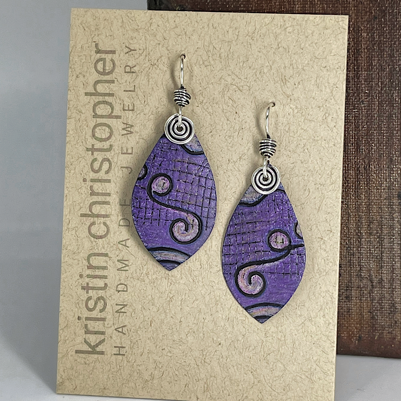 Purple earrings with silver designs on a 'Kristin Christopher' jewelry card.