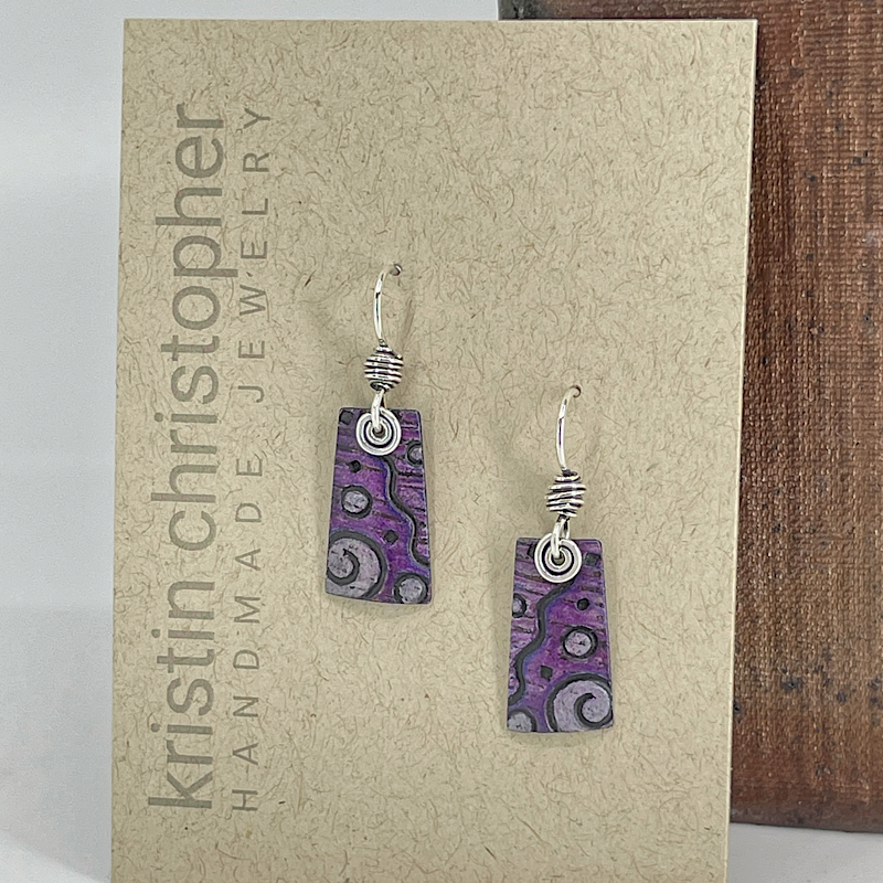 Purple patterned earrings on a 'Kristin Christopher' jewelry card.