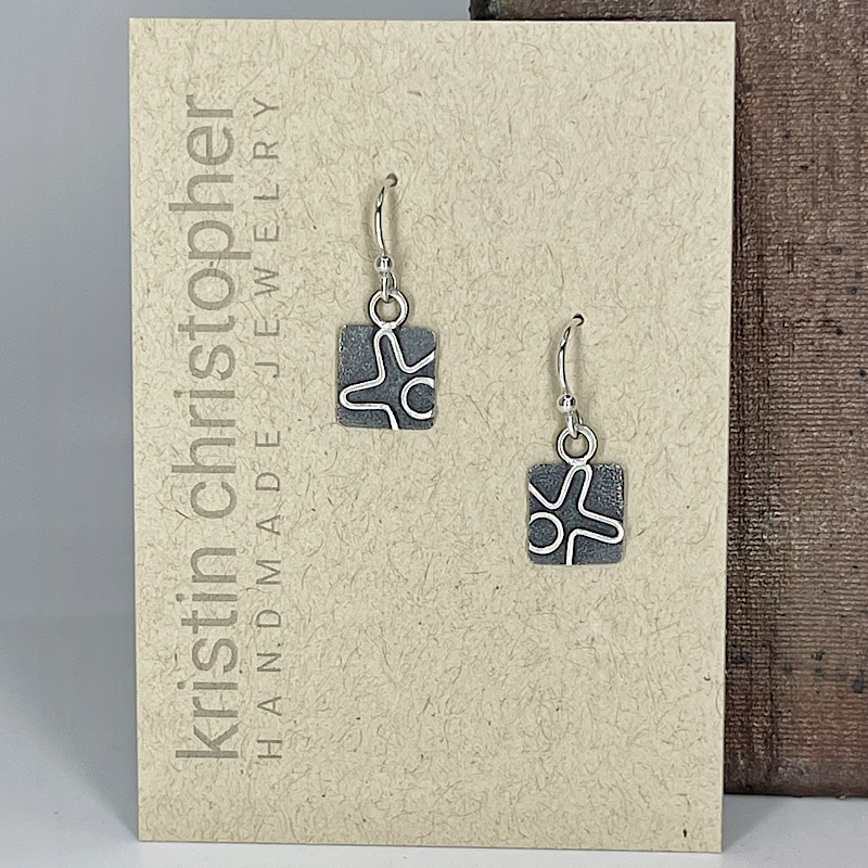 Pair of square silver earrings on a 'Kristin Christopher' branded card.
