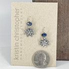 Sterling silver flower earrings with blue kyanite beads on a 'Kristin Christopher' card with a quarter for scale.