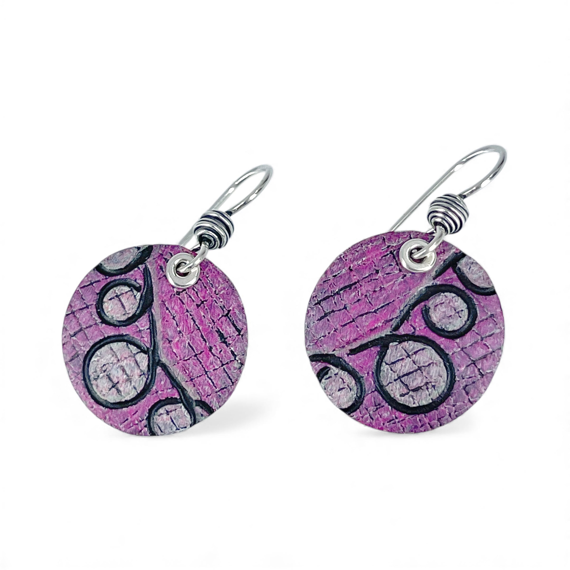 Pink circular earrings with black patterns on a white background