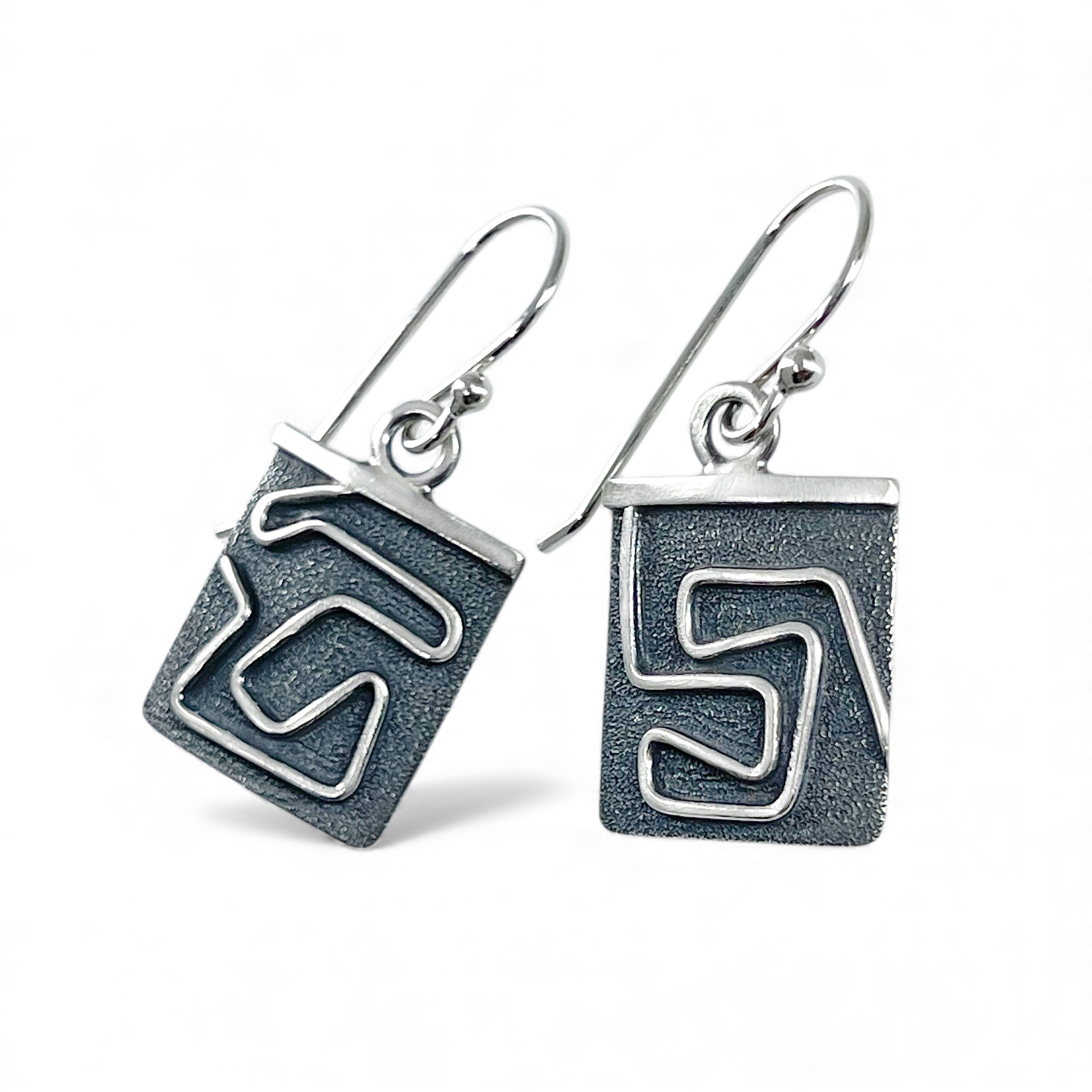 Pair of silver earrings with geometric design on a white background