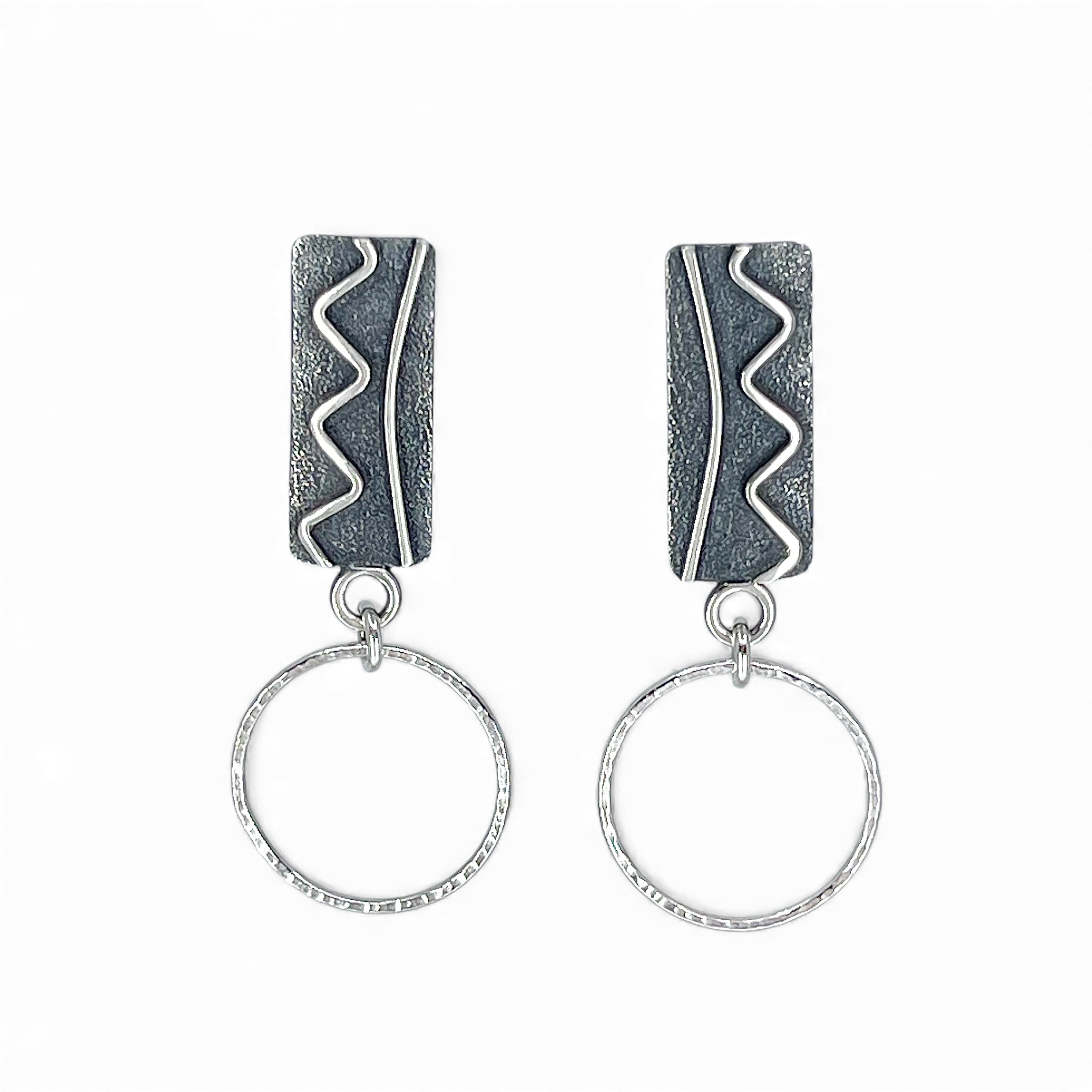 Sterling silver earrings with textured black and silver tops wtih silver hoops on a white background
