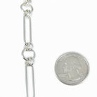 Handmade sterling silver circle and oval bracelet next to a quarter for scale