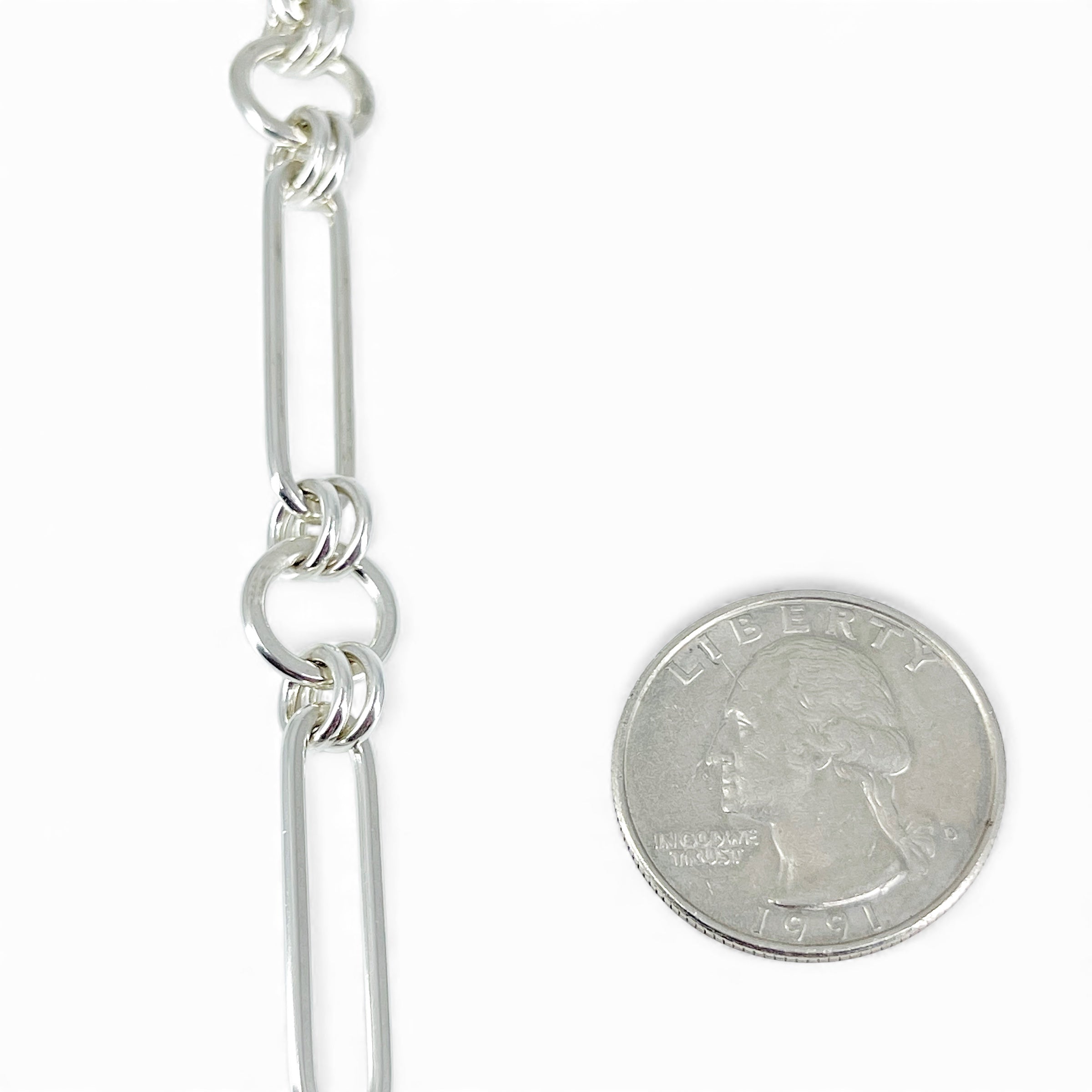 Handmade sterling silver circle and oval bracelet next to a quarter for scale